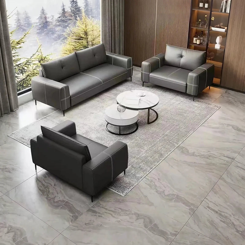 Visby gray leather conversation set around round nesting tables in a lounge with a forest window
