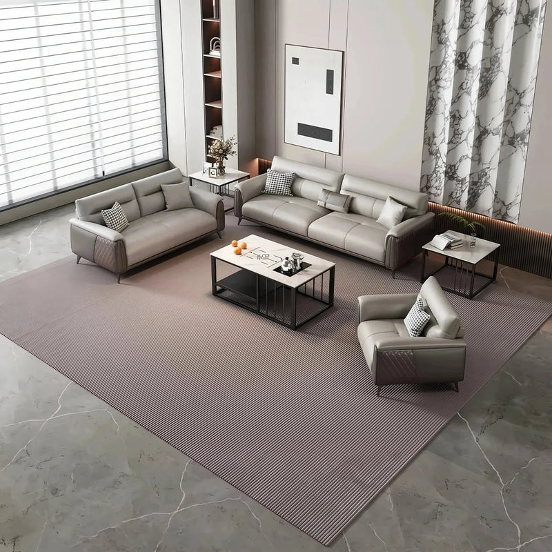 Hållö gray leather lounge set around a coffee table on a mauve rug in a room with window blinds
