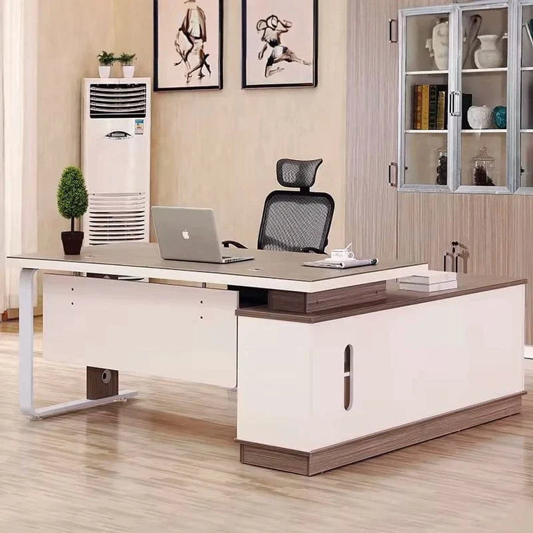 Home office with an L-shaped executive desk, bookcase, framed art and a plant