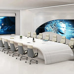 Calix white boardroom table with orange chairs facing curved digital wall displays in a futuristic meeting room
