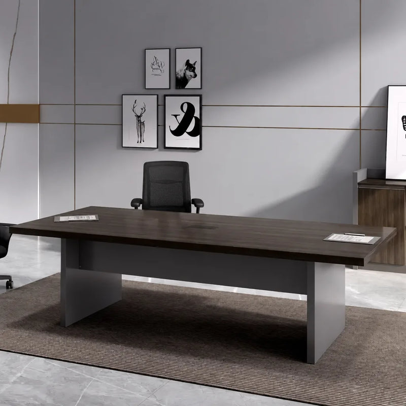 Maxum walnut meeting table with a single black chair in front of a gallery wall of framed prints