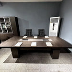 Prime brown conference table viewed straight on with notepads at each seat, client office photo